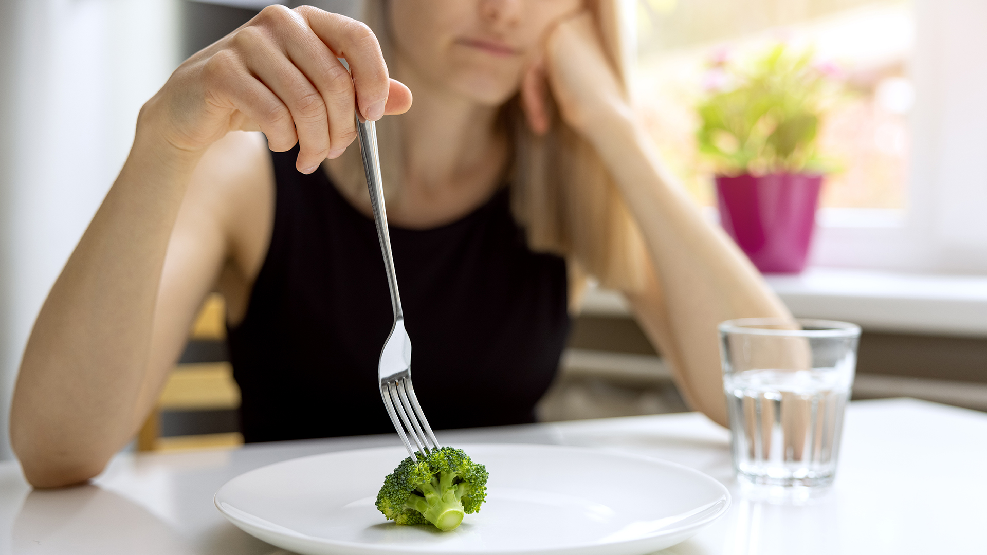 Frau isst ein Stück Brokoli
