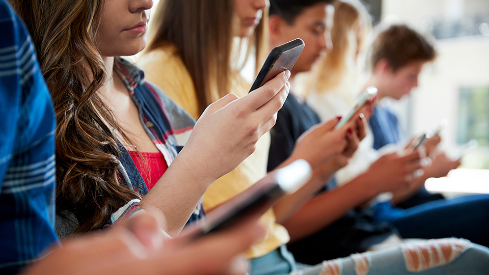 Schüler schauen alle auf ihre Handys. Link zur Fortbildung zum Thema Social-Media-Abhängigkeit bei Kindern und Jugendlichen.